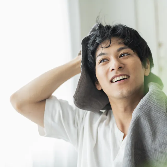 タオルを首にかけて笑う男性